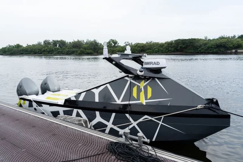 The HYARKS TF-100 moored alongside a dock, with its twin outboard engines and sensor mast visible
