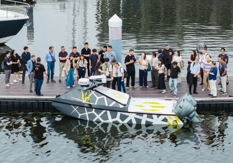 The TF-100 afloat beside guests at its launch event on 10 August 2026